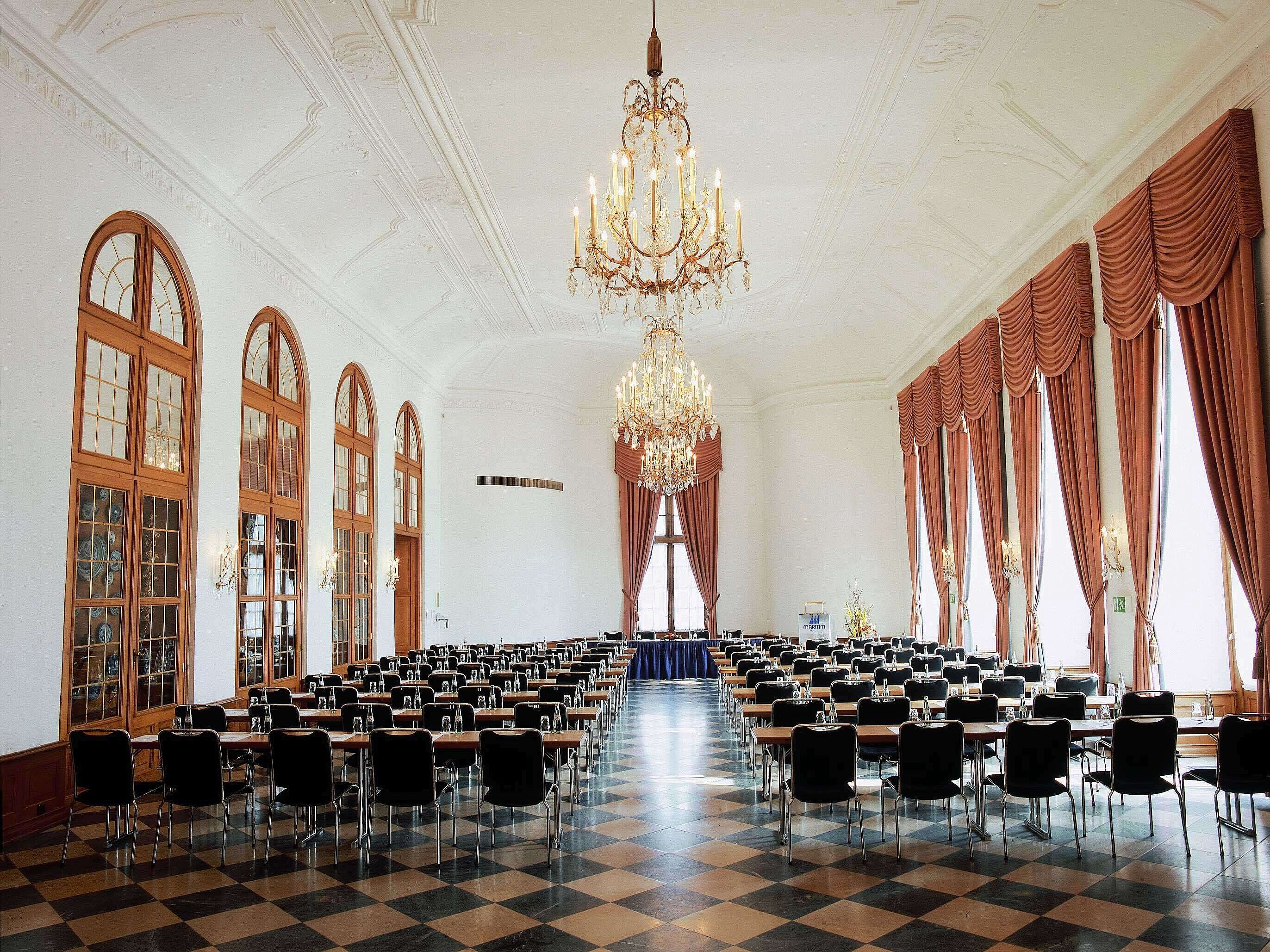 Salón de eventos elegante en Maritim Hotel Fulda con lámparas, ventanales altos y asientos sofisticados.