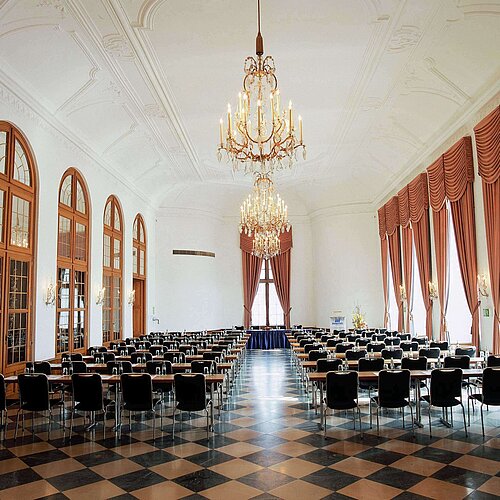 Salón de eventos elegante en Maritim Hotel Fulda con lámparas, ventanales altos y asientos sofisticados.