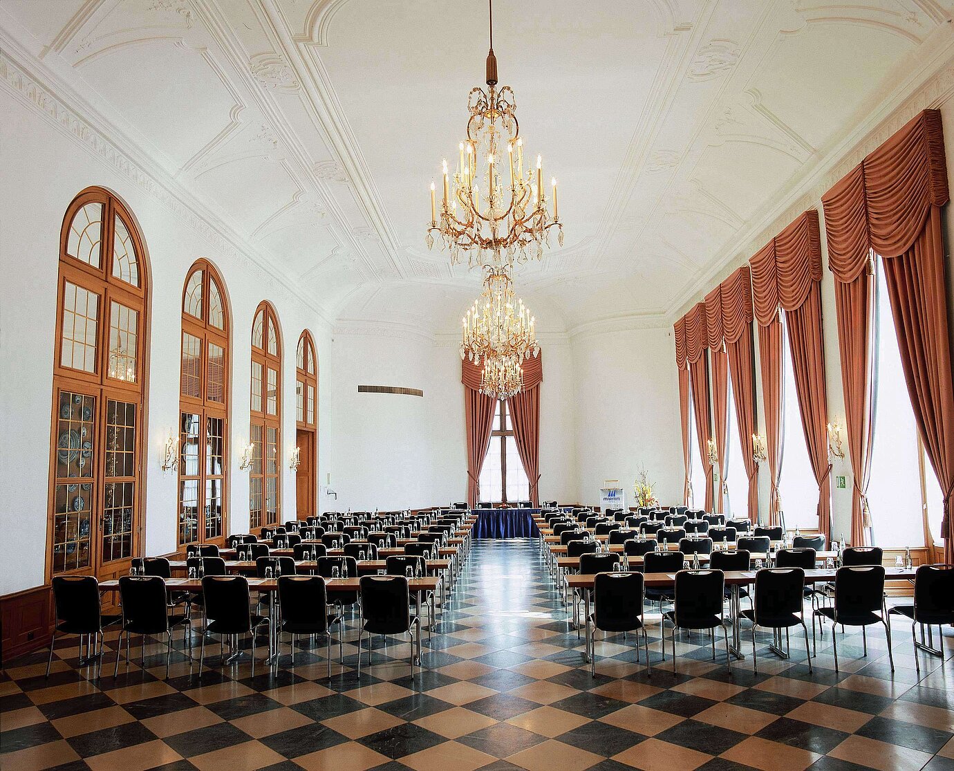 Salón de eventos elegante en Maritim Hotel Fulda con lámparas, ventanales altos y asientos sofisticados.
