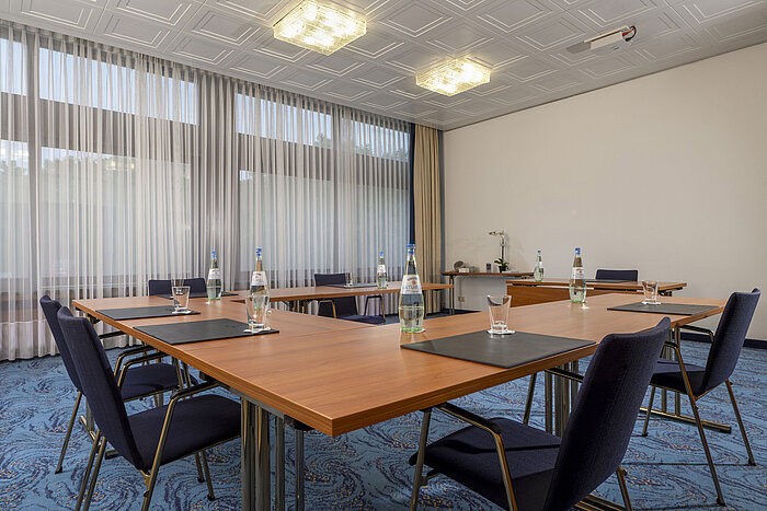 Sala en U con sillas azules y luz natural en el Maritim Hotel Travemünde
