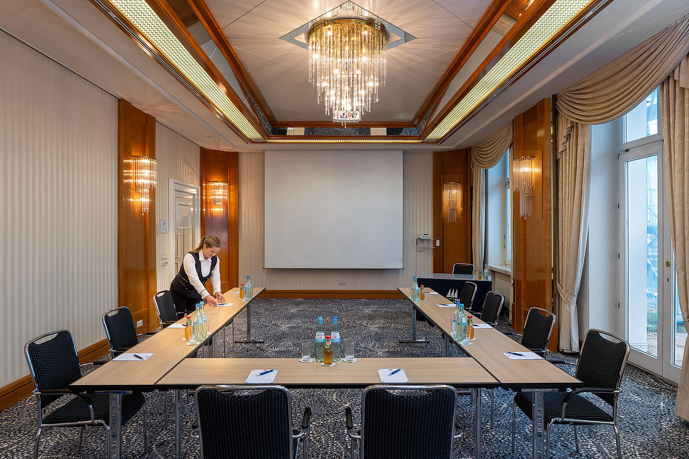 Elegant meeting room at a Maritim hotel with U-shaped table setup and projection screen.
