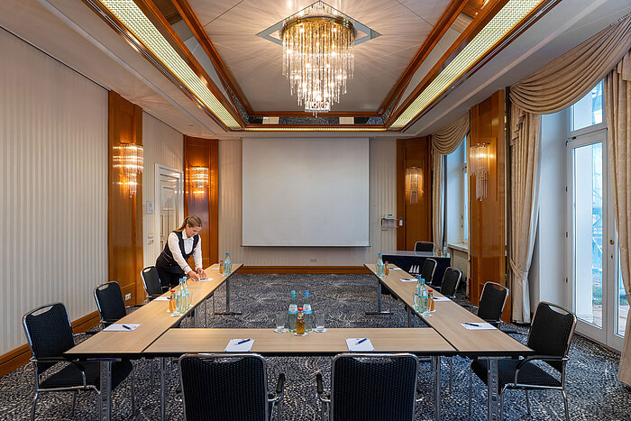 Elegant meeting room at a Maritim hotel with U-shaped table setup and projection screen.