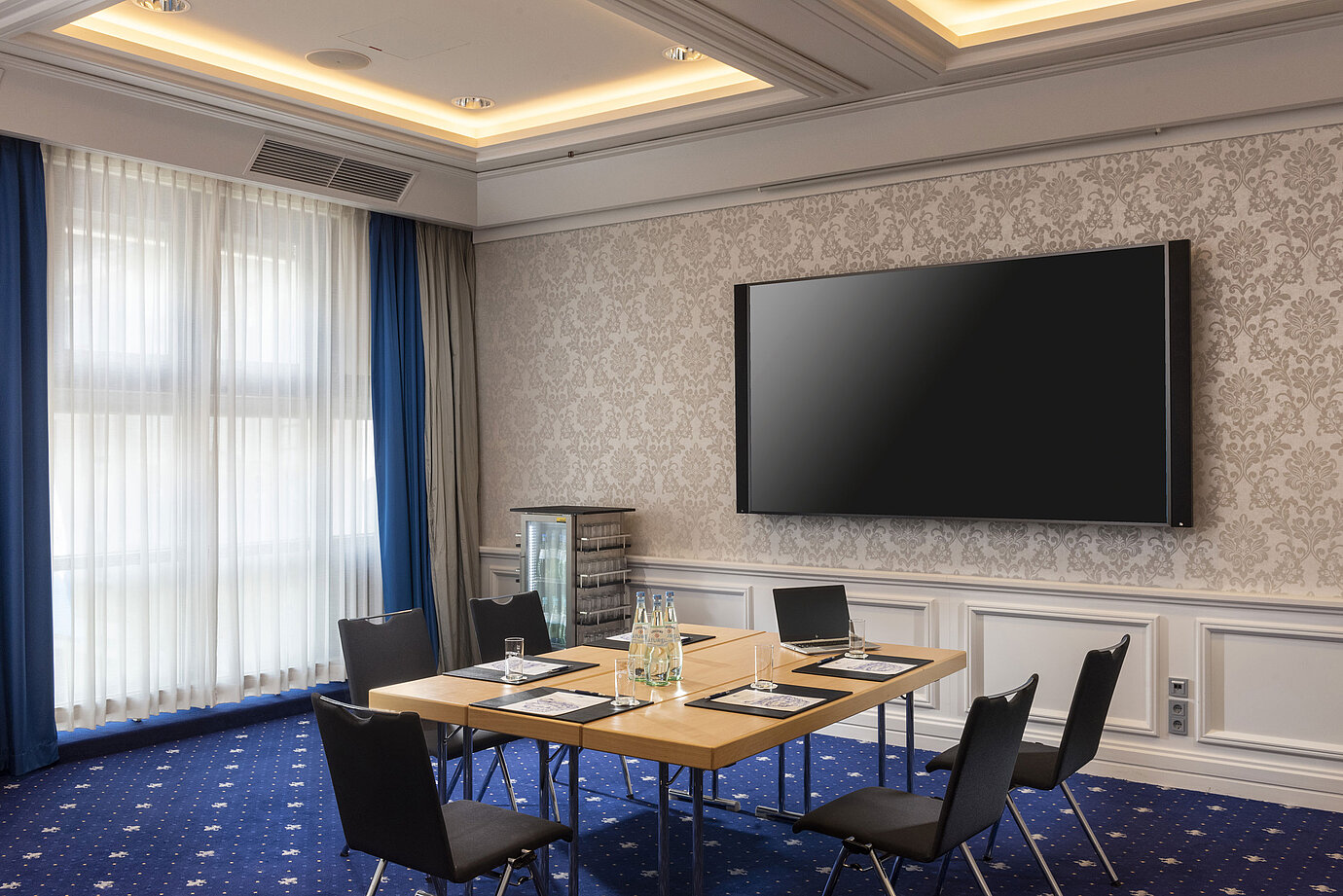 Sala de conferencias en el Maritim Hotel Würzburg con equipamiento moderno y pantalla grande.