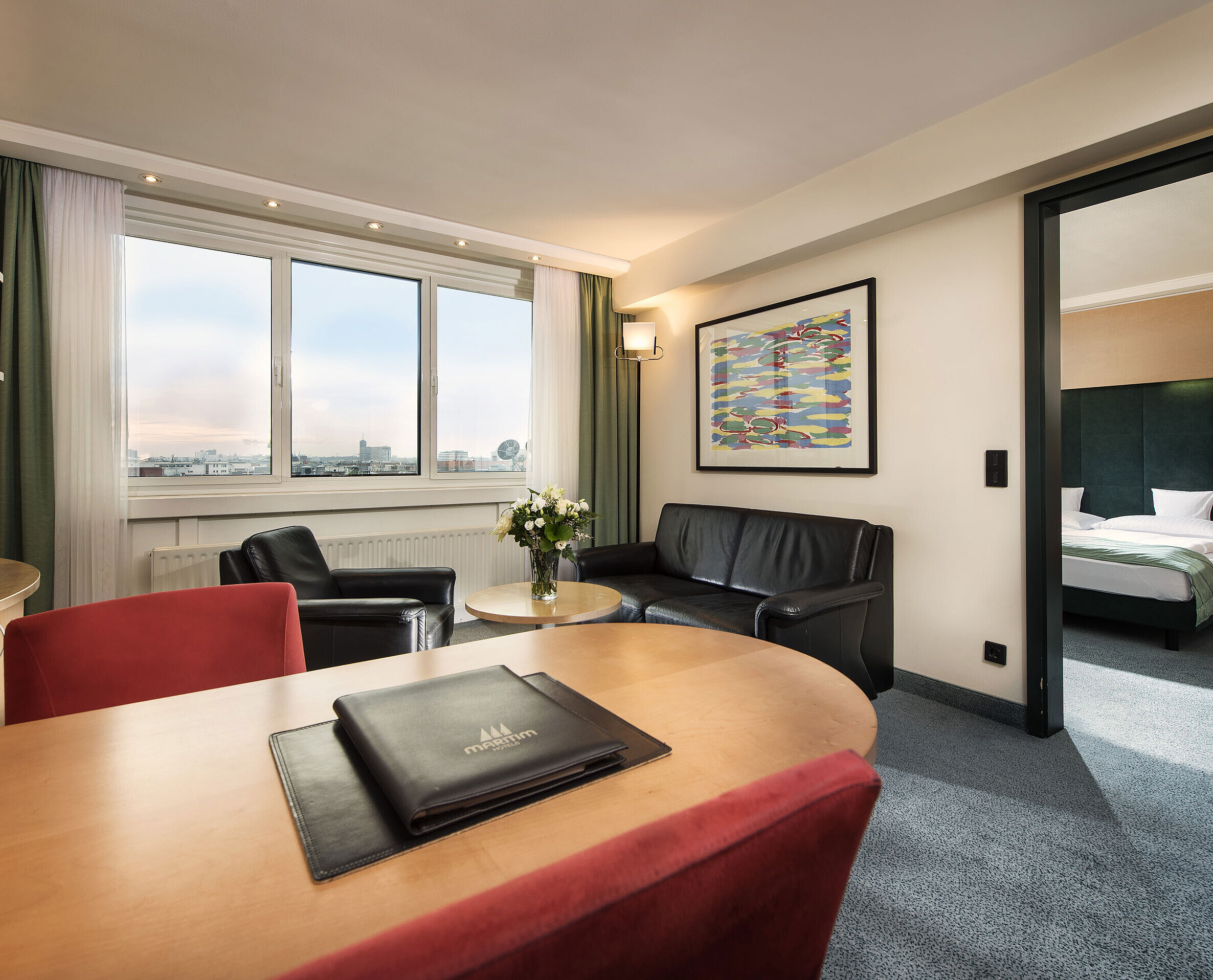 Suite di familglia Junior suite al Maritim proArte Hotel Berlino con soggiorno, scrivania, divano e camera separata con letto king-size.