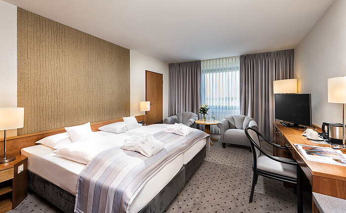Camera doppia Superior con letto king-size, accappatoi, area salotto e scrivania al Maritim Hannover.
