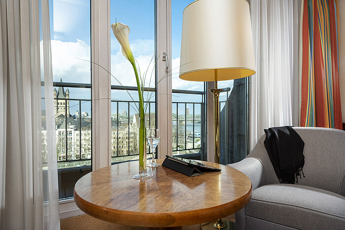 Chambre Classic à l'Hôtel Maritim Cologne avec vue sur le Rhin, coin salon confortable et table décorée avec élégance.