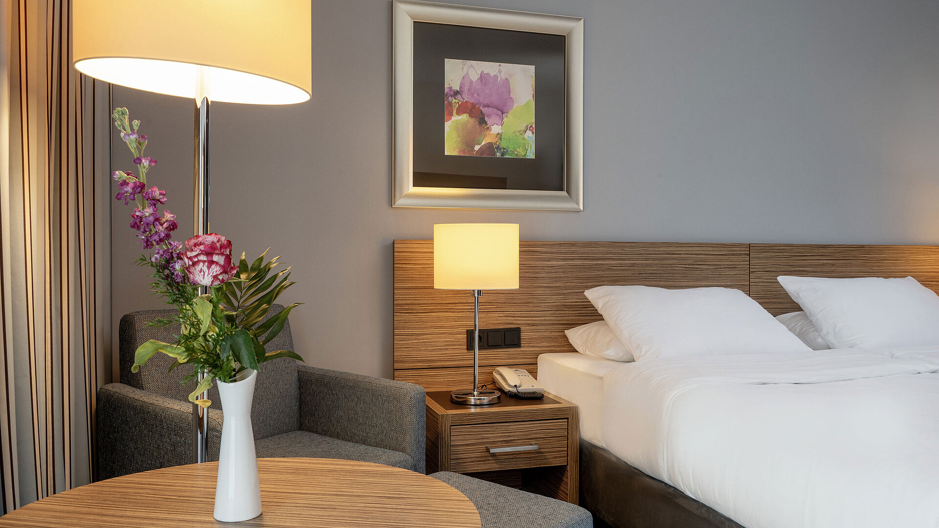 Accogliente angolo salotto con vaso di fiori accanto al comodo letto nella camera Superior del Maritim Hotel Darmstadt