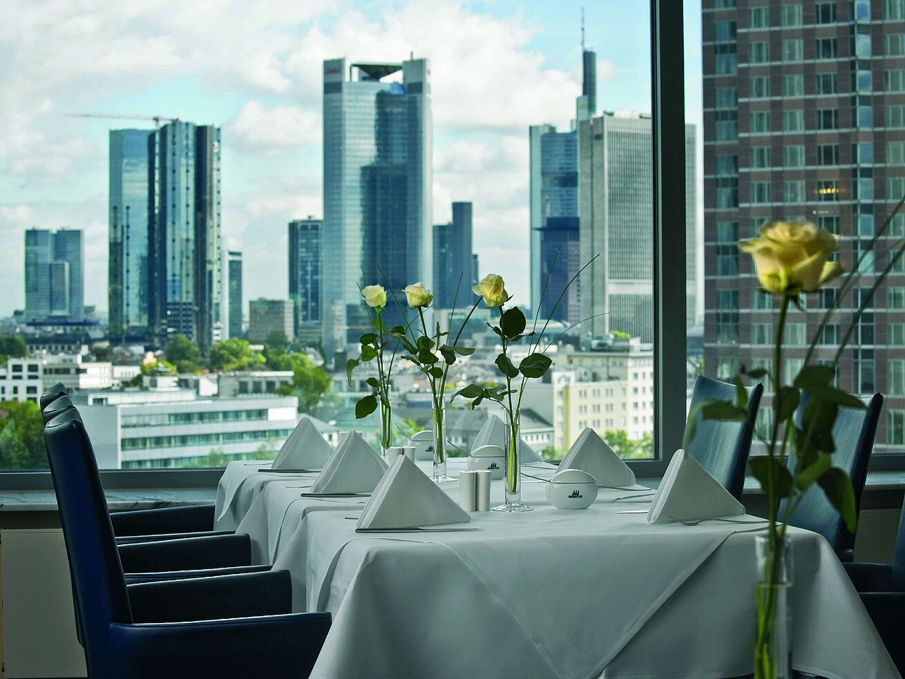 Comedor elegante con vista al skyline y mesa preparada en la SkyLounge del Maritim Hotel Frankfurt.