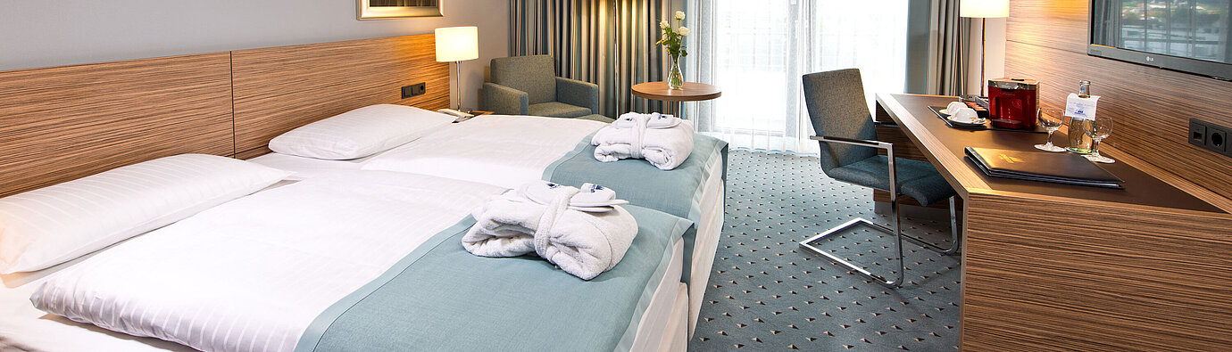 Superior room at Maritim Hotel Darmstadt featuring stylish design, desk, cozy seating area, and double bed with bathrobes.