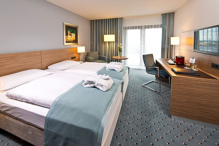 Superior room at Maritim Hotel Darmstadt featuring stylish design, desk, cozy seating area, and double bed with bathrobes.