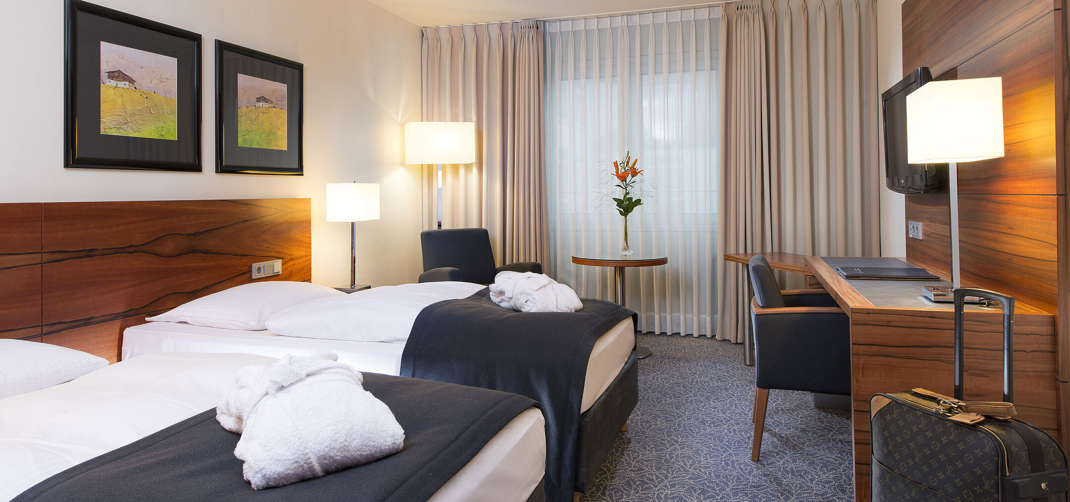 Chambre twin confortable à l'hôtel Maritim de Munich. Avec lits séparés, bureau, TV et coin salon près de la fenêtre.
