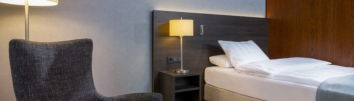 Chambre Superior moderne au Maritim Hotel Bremen avec fauteuil confortable, table de chevet et éclairage d'ambiance.