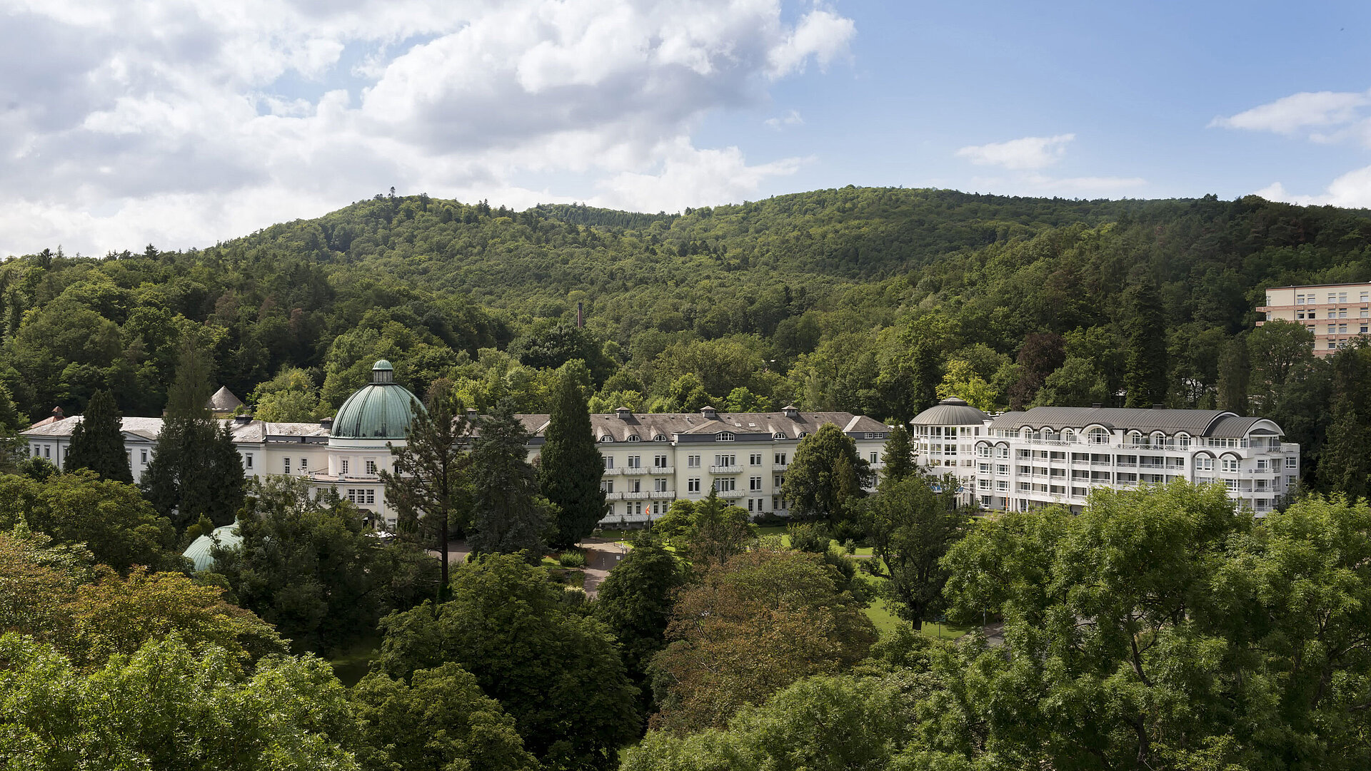 Exterior view of Maritim Hotel Bad Wildungen surrounded by lush greenery in summer