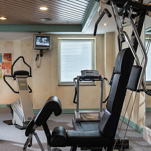 Palestra al Maritim Hotel Magdeburg con attrezzature moderne come tapis roulant, cyclette e stazione multifunzione.