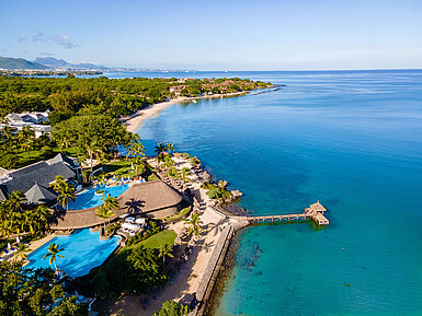 Vista esterna Vista aerea di un resort sul mare con piscina, palme e accesso diretto all’acqua turchese