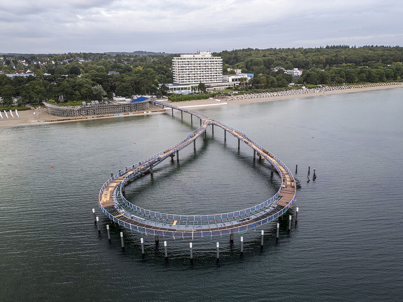 Pont maritime Maritim Jetée devant le Maritim Seehotel Timmendorfer Strand avec eau calme et ciel bleu.