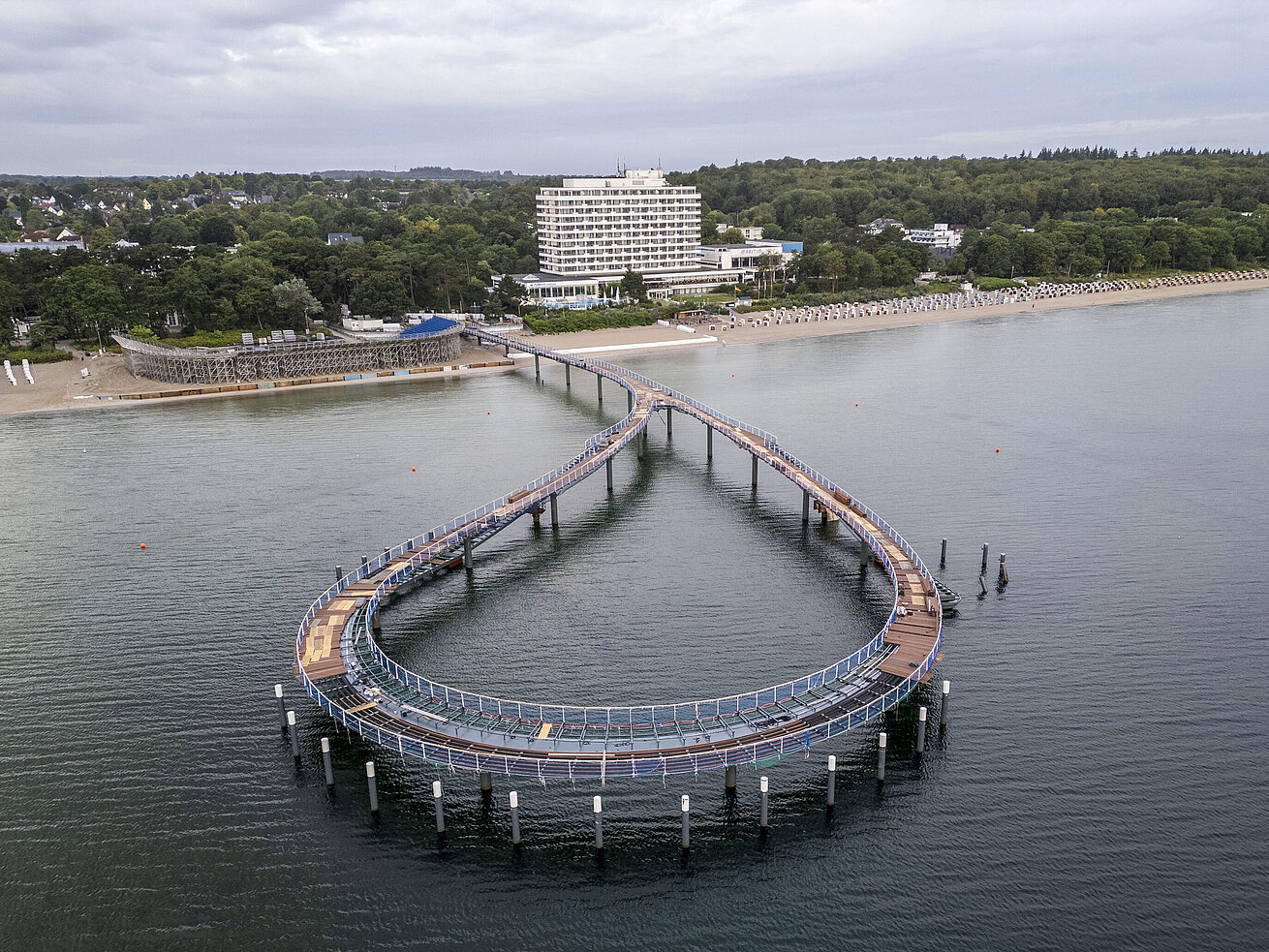 Pier in front of the Maritim Seehotel Timmendorfer Strand with calm water and blue sky.