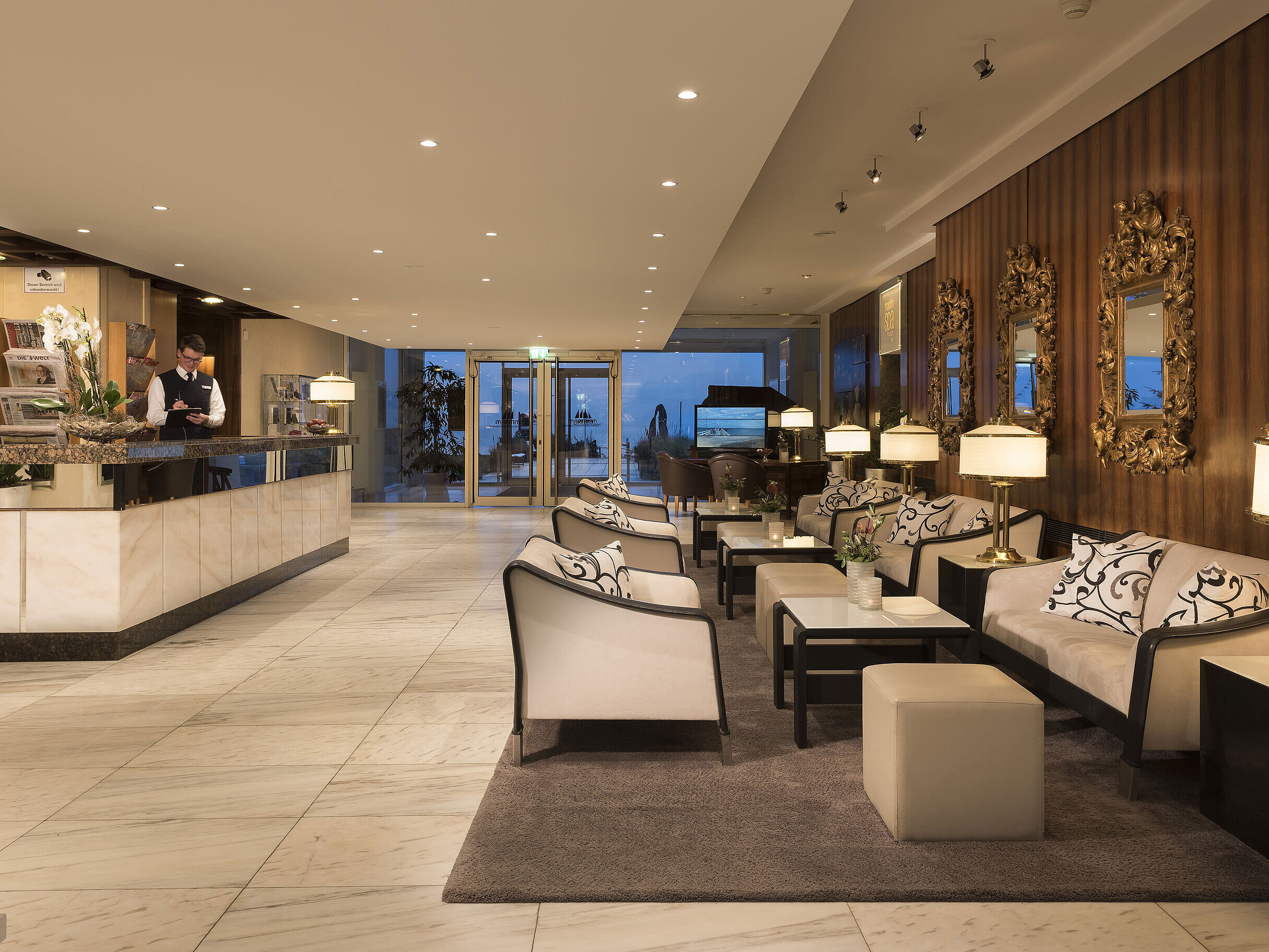 Reception e lobby con area salotto al Maritim Seehotel Timmendorfer Strand con illuminazione serale.