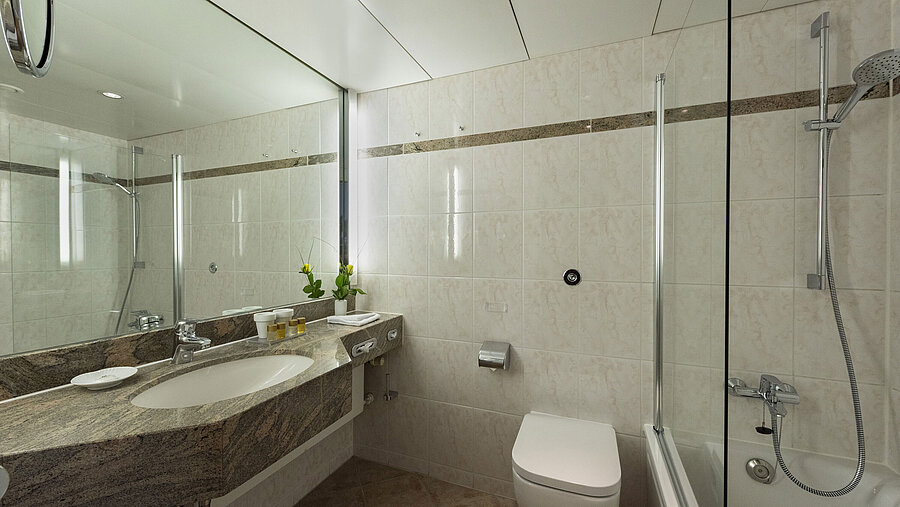 Salle de bains lumineuse avec plan vasque en granit, miroir et douche – Maritim Hotel Travemünde