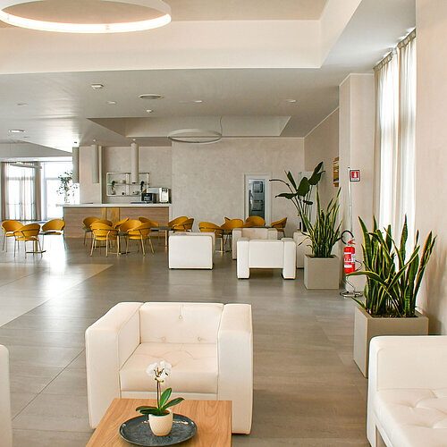 Hall lumineux du Maritim Resort Calabria avec fauteuils blancs et chaises jaunes