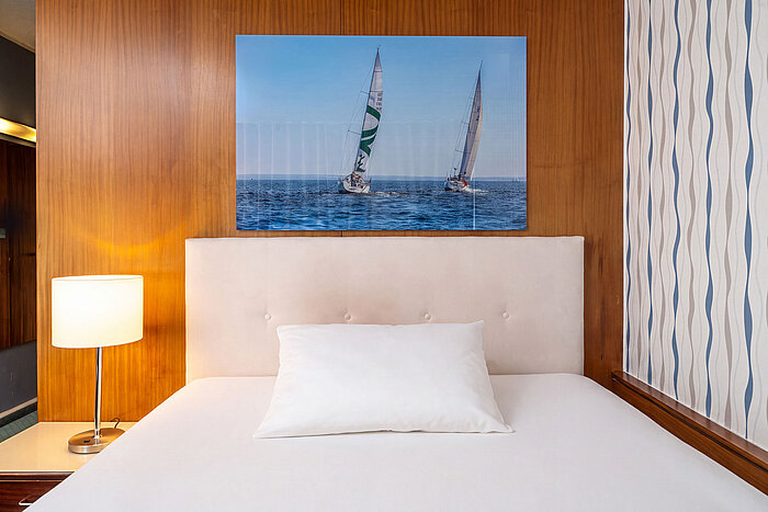 Letto queen-size nella camera Classic Queen con lampada da comodino e decorazione murale a tema marittimo