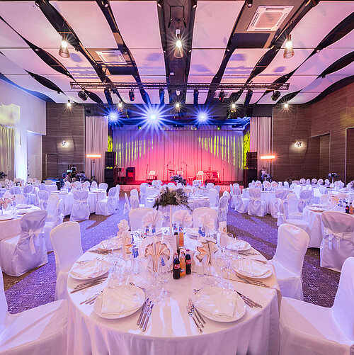 Salle de banquet élégante avec tables rondes, scène et éclairage coloré