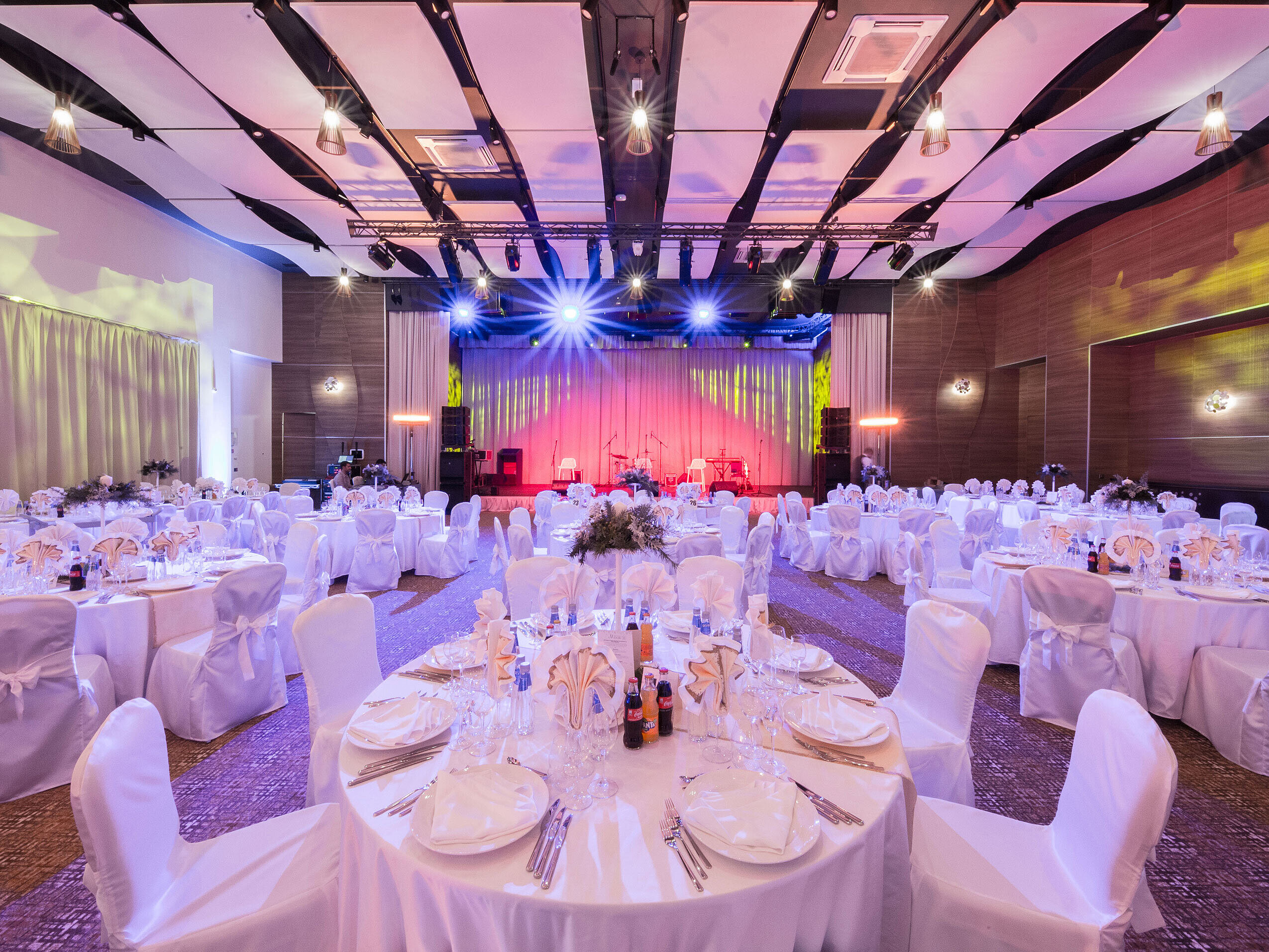 Salle de banquet élégante avec tables rondes, scène et éclairage coloré