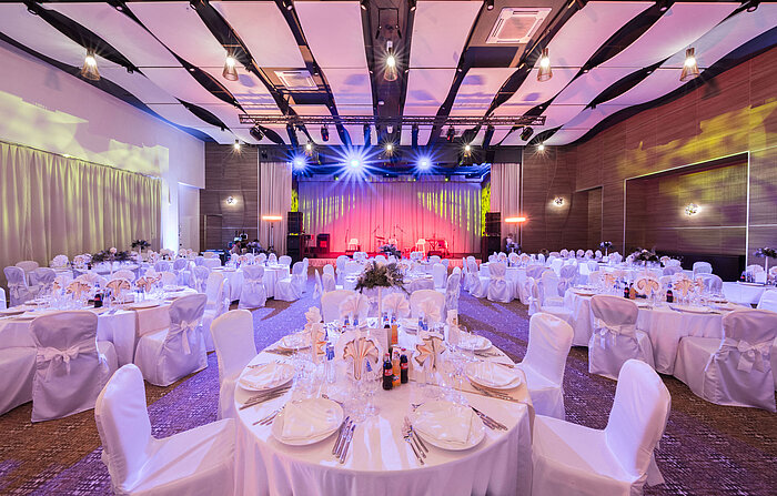 Salle de banquet élégante avec tables rondes, scène et éclairage coloré