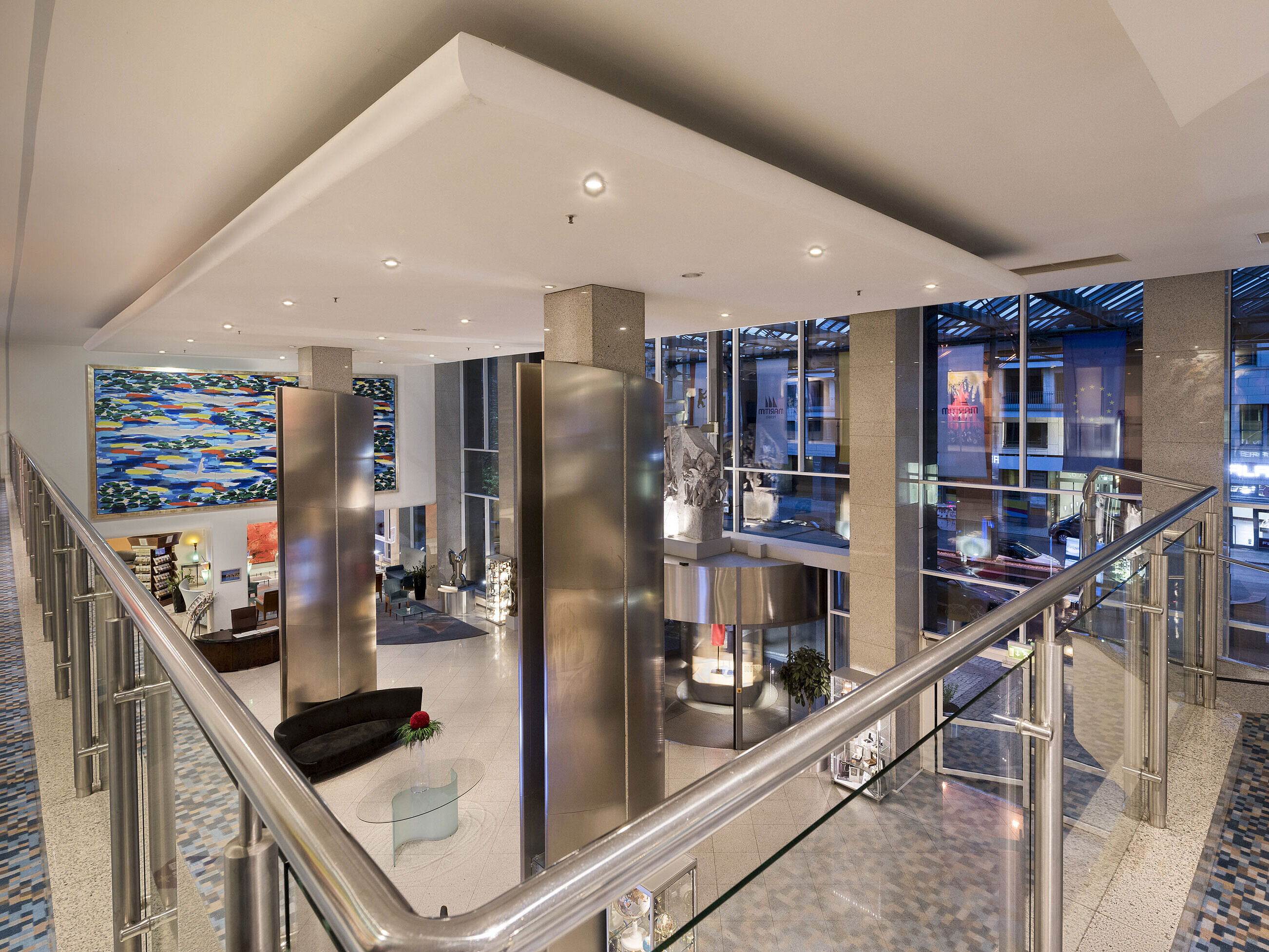 Overhead view of the modern lobby at the Maritim proArte Hotel Berlin with large artwork and glass walls.