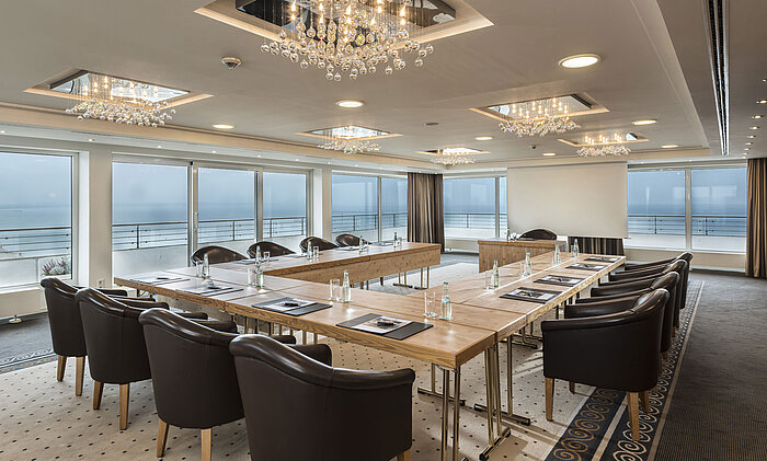 Salón Hamburgo en Maritim Seehotel Timmendorfer Strand, sala de reuniones con vista al mar, mesa en L y luces elegantes.