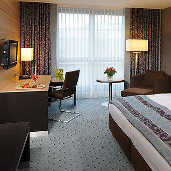 Habitación Superior en el Maritim Hotel Düsseldorf con cama doble elegante, escritorio moderno, zona de estar cómoda.