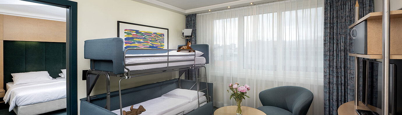 Family suite with bunk bed, sofa, table and view into bedroom at Maritim proArte Hotel Berlin