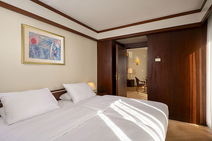 Camera da letto luminosa con letto matrimoniale e opera d'arte nella Senior Suite del Maritim Hotel Köln