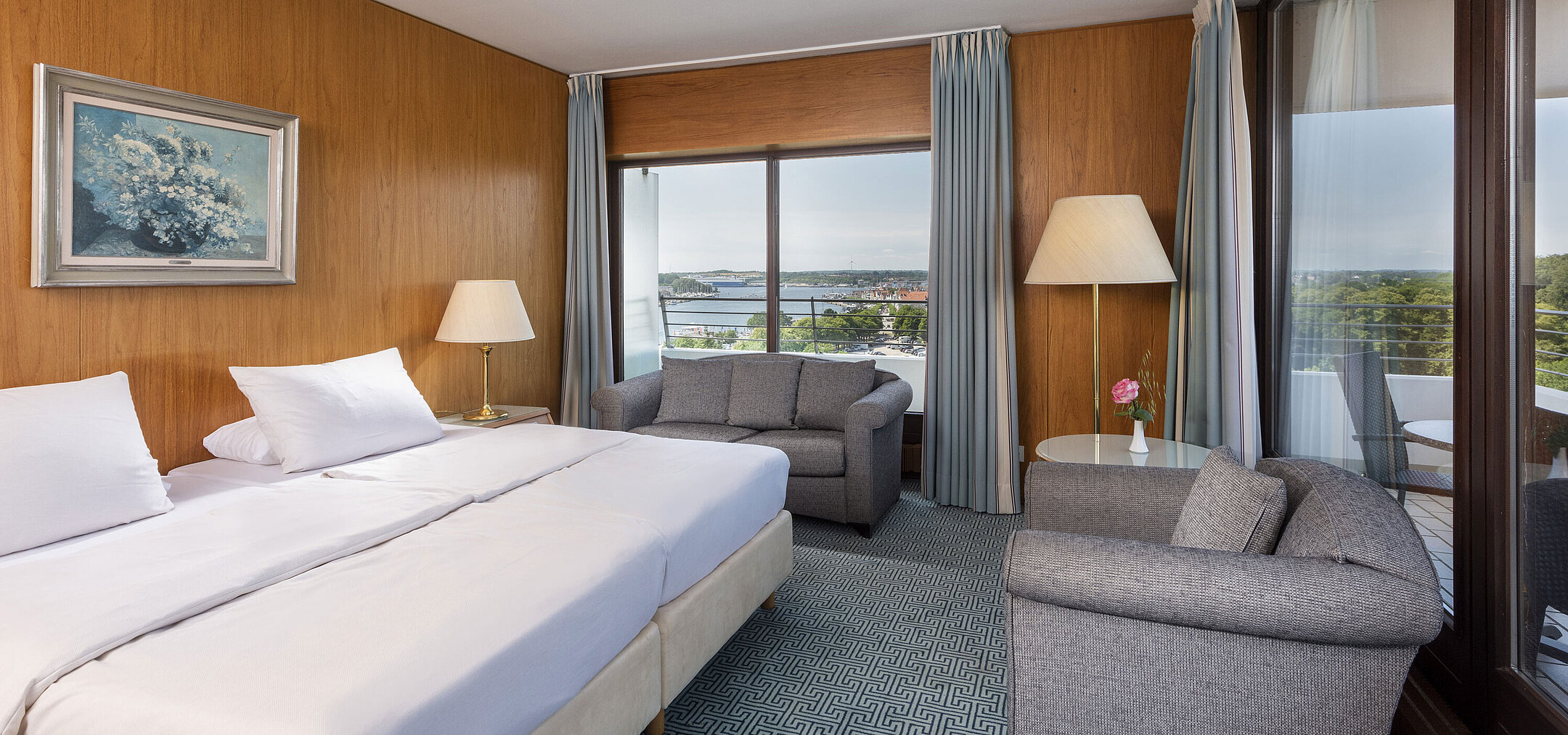 Chambre double moderne avec coin salon cosy et grande fenêtre avec vue sur la baie de Lübeck