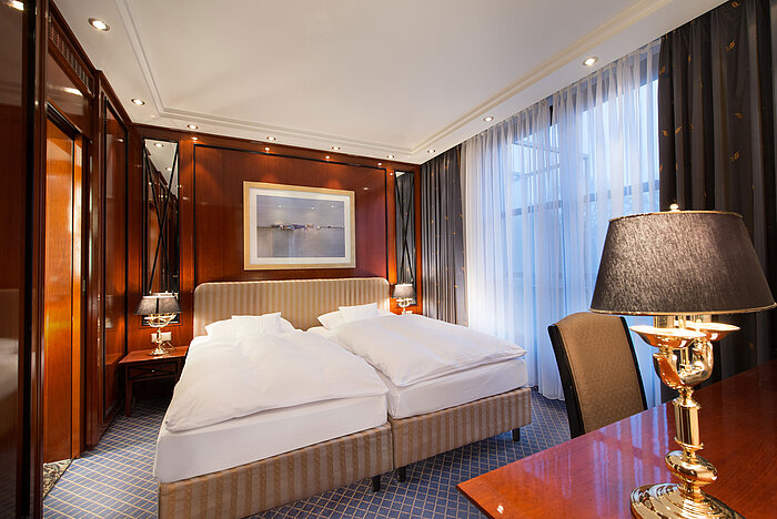 Suite elegante en Maritim Hotel Fulda con cama doble de lujo, detalles en madera e iluminación acogedora.