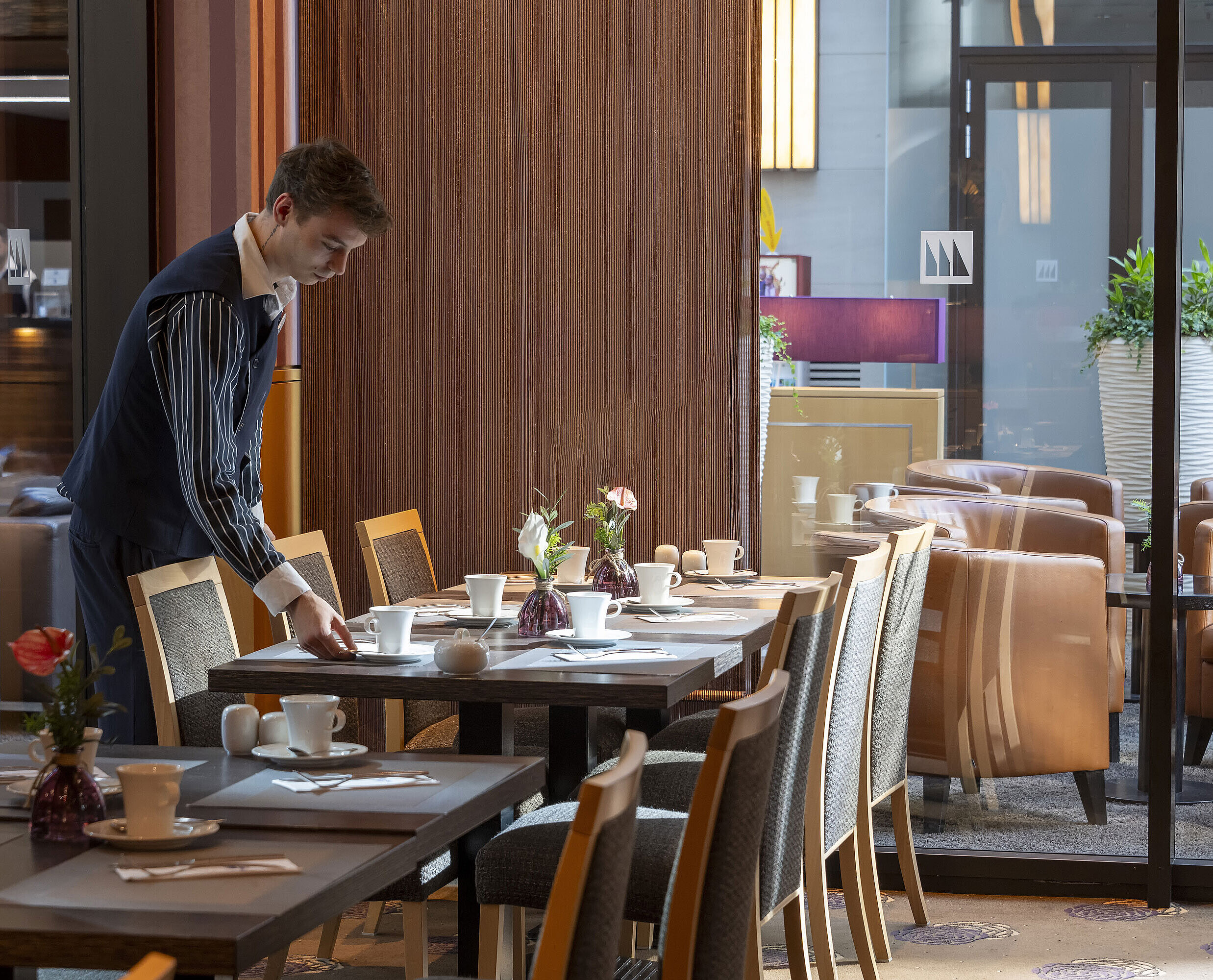 Restaurant Classico Membre du personnel préparant une table au restaurant Classico de l'hôtel Maritim Düsseldorf,entouré d'une décoration élégante