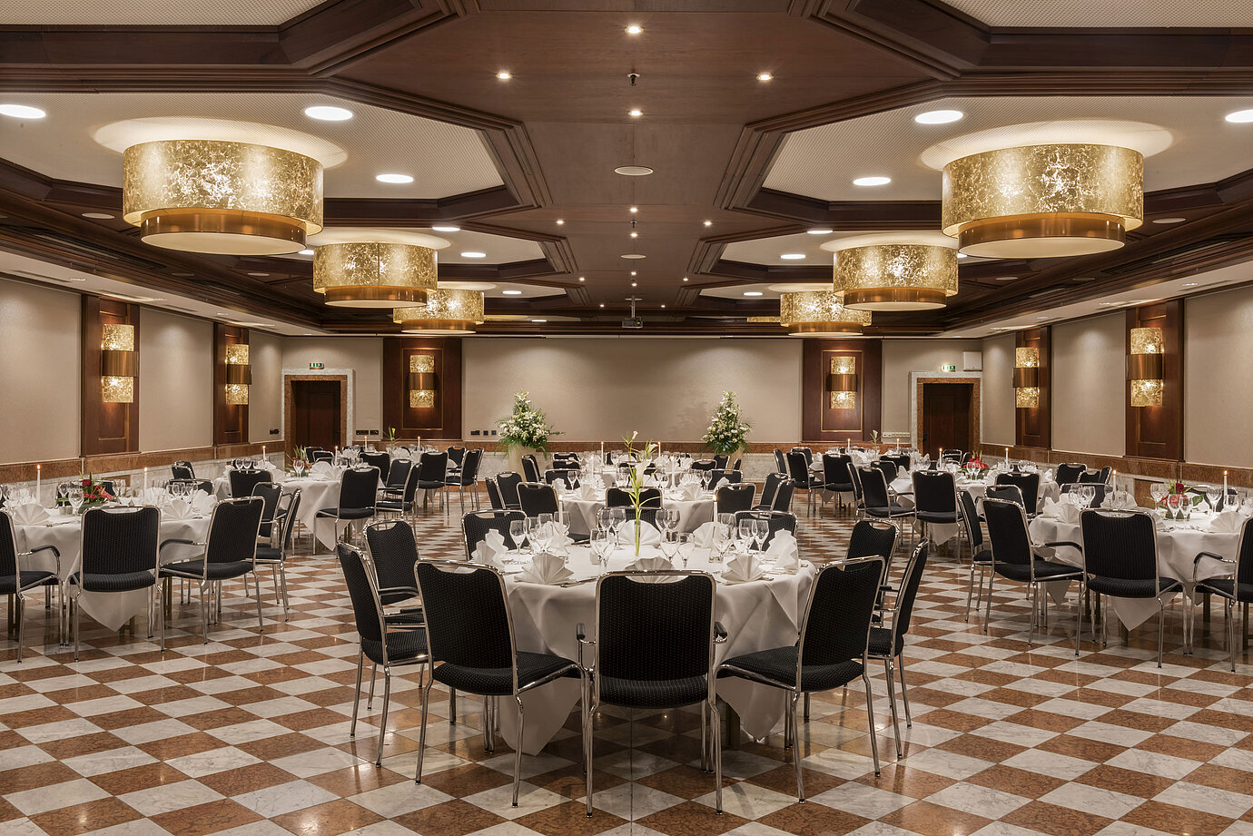 Elegante salón de eventos en Maritim Hotel Königswinter con mesas redondas, decoración elegante y lámparas.