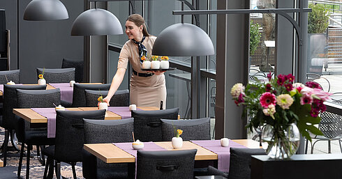 Wintergarten Restaurant Staff member preparing neatly set tables at Restaurant Wintergarten at Maritim Hotel Dresden.