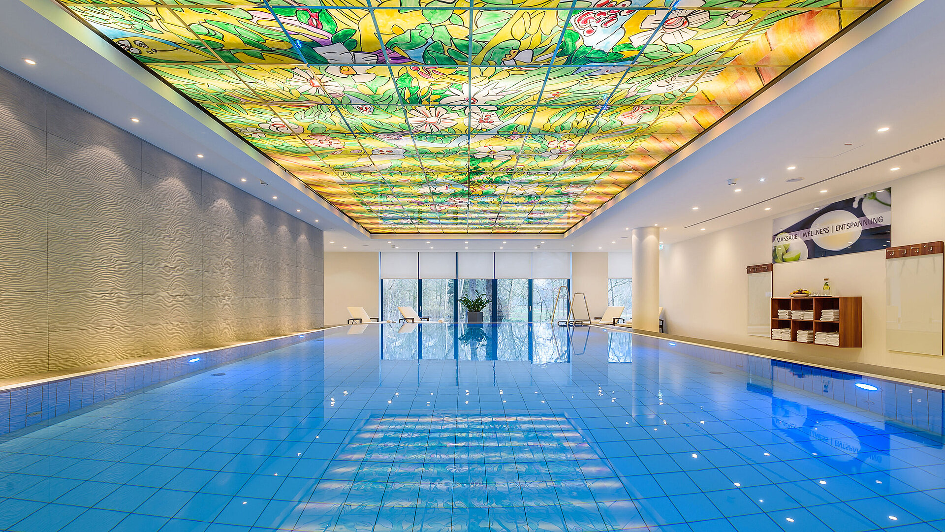 Élégant espace piscine au Maritim Bremen avec plafond en verre coloré et éclairage moderne, idéal pour bien-être et détente.