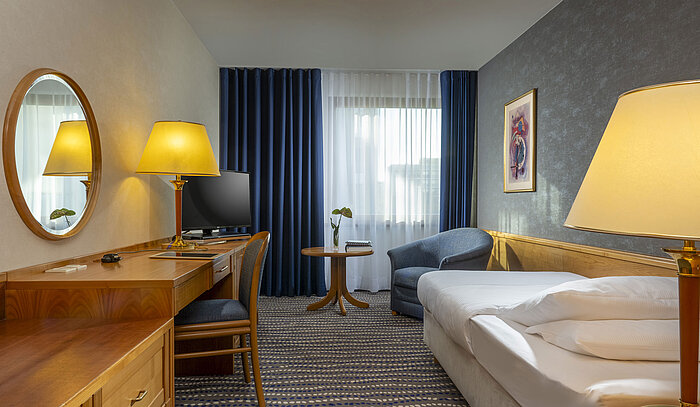 Chambre avec bureau, lit et fauteuil à l’hôtel Maritim Magdebourg