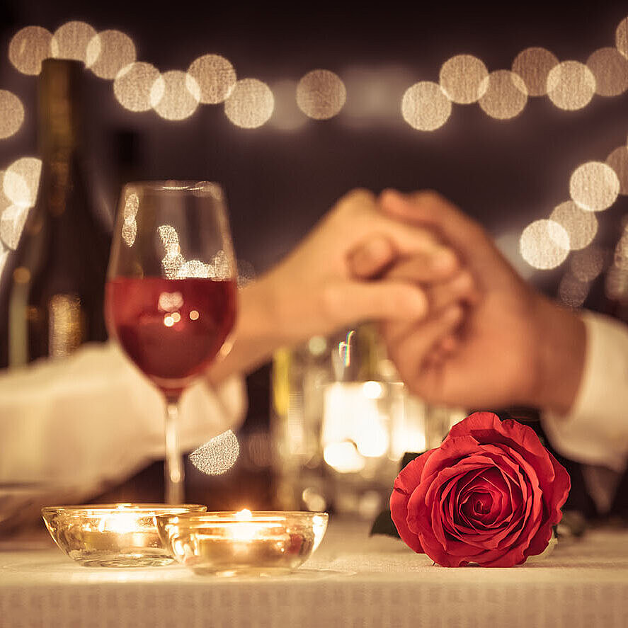 © kieferpix - AdobeStock.com Romantic candlelight dinner with red wine, roses and soft lights