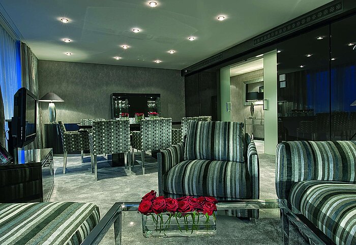 Salon élégant de la Master Suite au Maritim Düsseldorf avec sièges modernes, table à manger stylée et éclairage chaleureux.