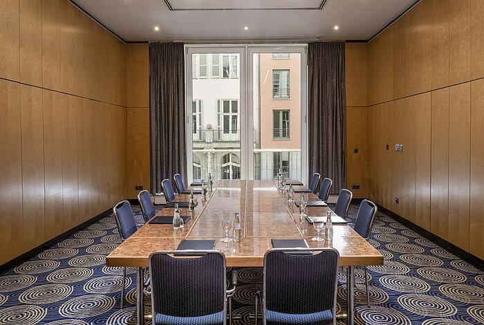 Sala de reuniones luminosa Salón I en el Hotel Maritim proArte Berlín con gran mesa de conferencia y vista exterior.