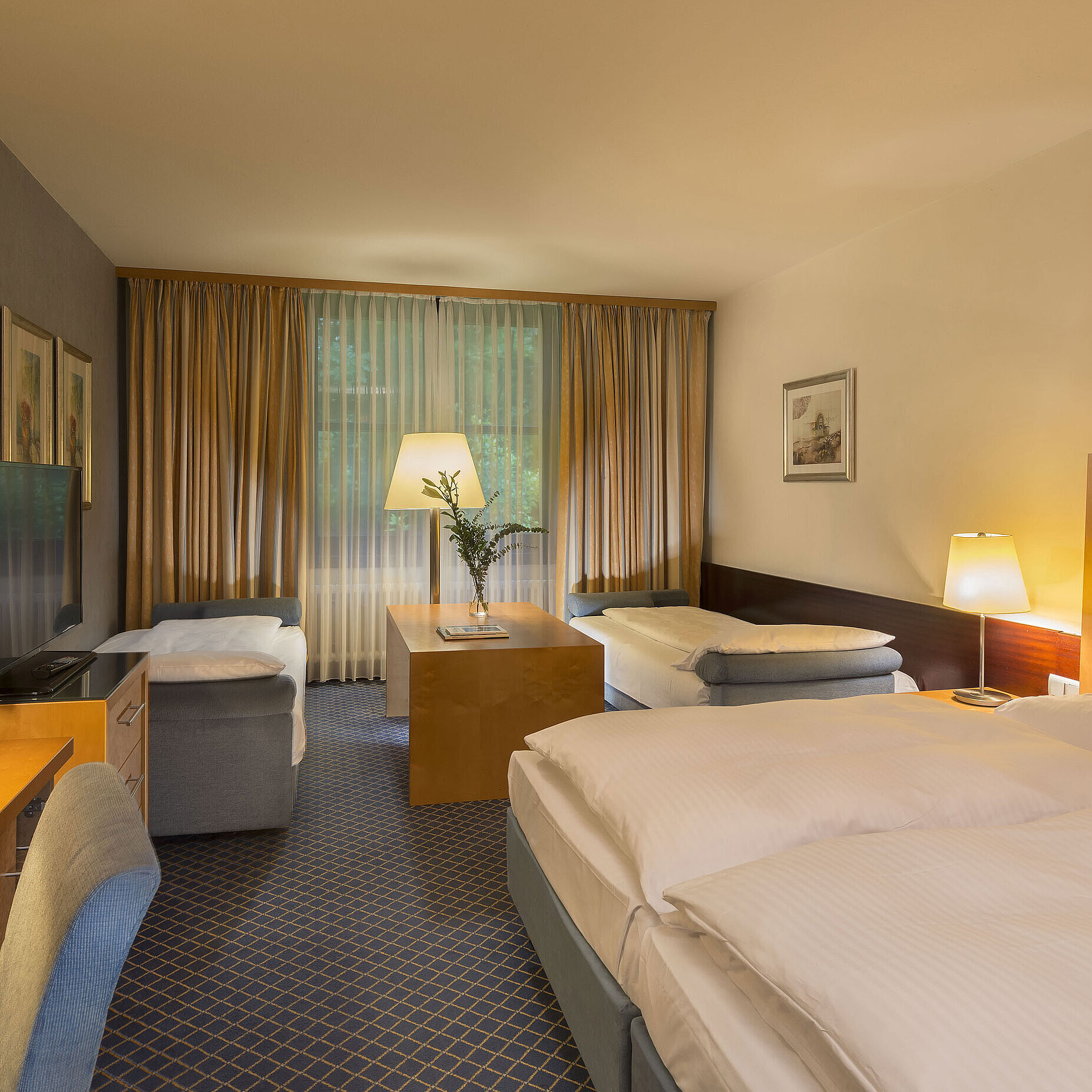 Family room Spacious family room at Maritim Hotel Fulda with four beds, desk, and cozy atmosphere.