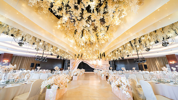 Salle de mariage magnifiquement décorée avec plafond floral, scène élégante et sièges raffinés