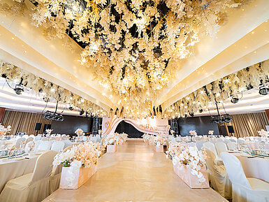 Salle de mariage magnifiquement décorée avec plafond floral, scène élégante et sièges raffinés