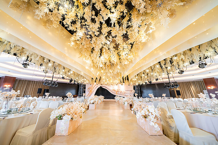 Sala per matrimoni splendidamente decorata con soffitto floreale, palco elegante e sedute raffinate