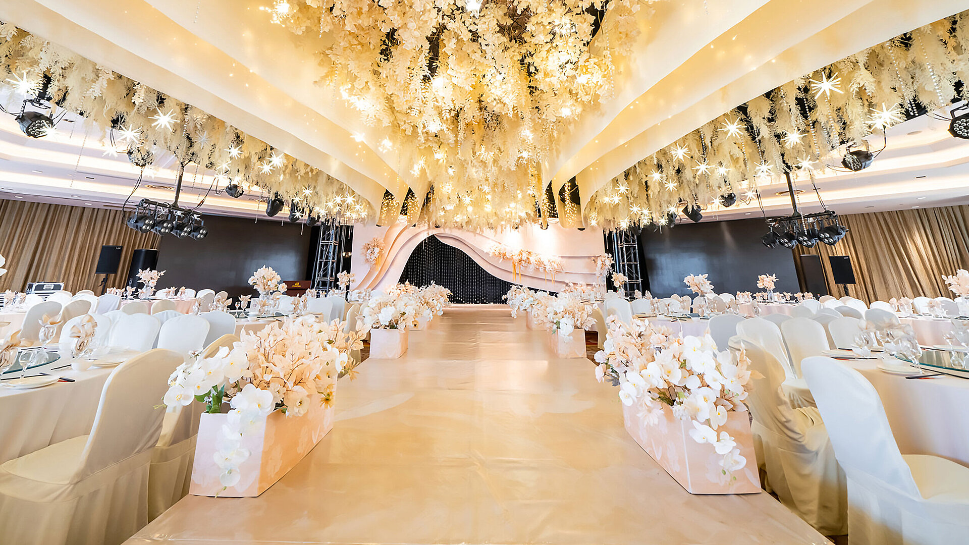 Salle de mariage magnifiquement décorée avec plafond floral, scène élégante et sièges raffinés