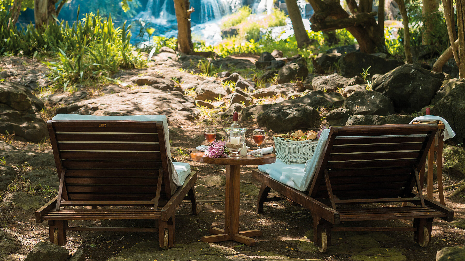 Deux chaises longues avec table en pleine nature face à une cascade