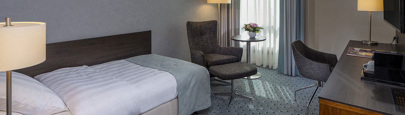 Chambre simple supérieure confortable au Maritim Hotel Bremen avec bureau, fauteuil et design moderne.